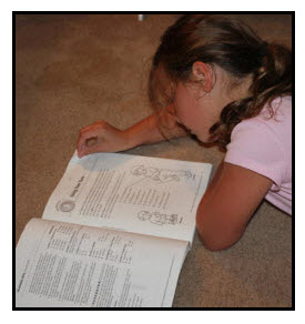Girl is researching by reading a book.