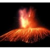 A picture of a volcano erupting at night.Fire is shooting upward from the opening and hot lava is pouring down the sides of the volcano.